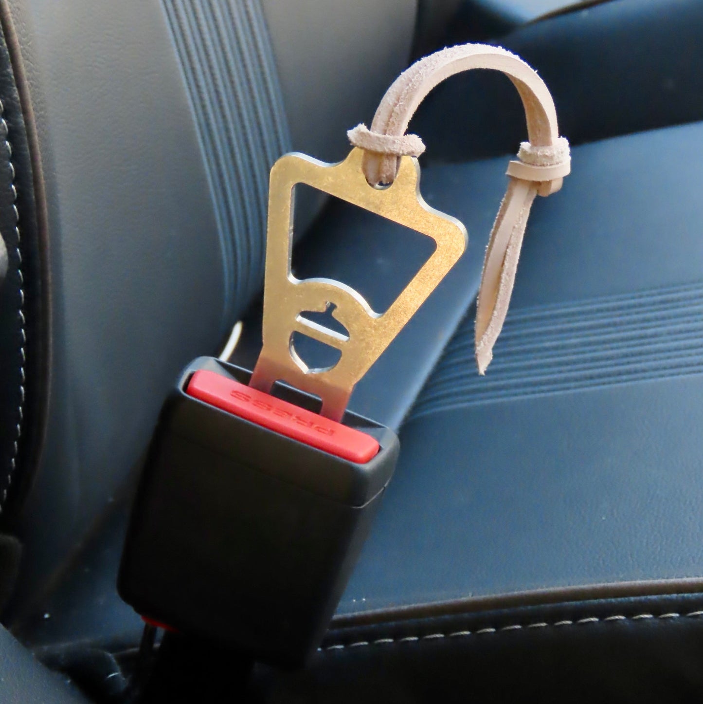 Car seat belt clip with bottle opener attached to a car seat.