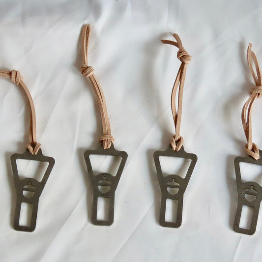 Four metal bottle openers with leather straps on a white background