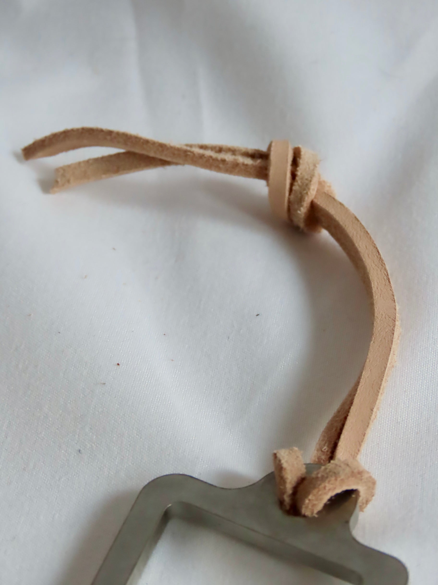 Metal object with a brown leather strap on a white background